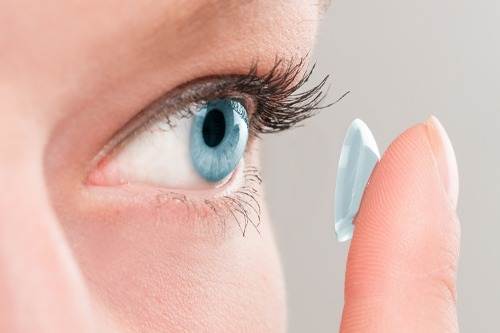 Upclose shot of woman's face, about to insert contact lens into eye